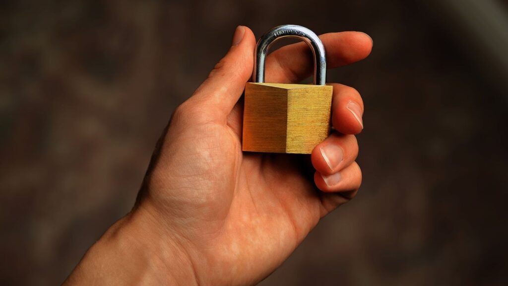 Close-up of a hand holding a small brass padlock