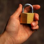 Close-up of a hand holding a small brass padlock