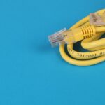 Close-up of a yellow Ethernet cable with connectors coiled on a blue background