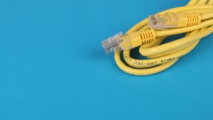 Close-up of a yellow Ethernet cable with connectors coiled on a blue background