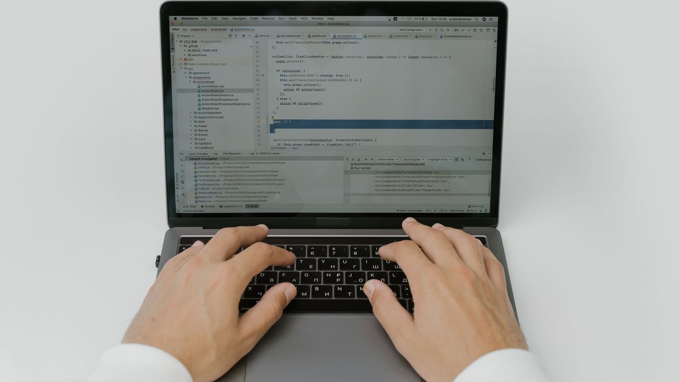 A developer's hands on a laptop keyboard in front of an open code editor