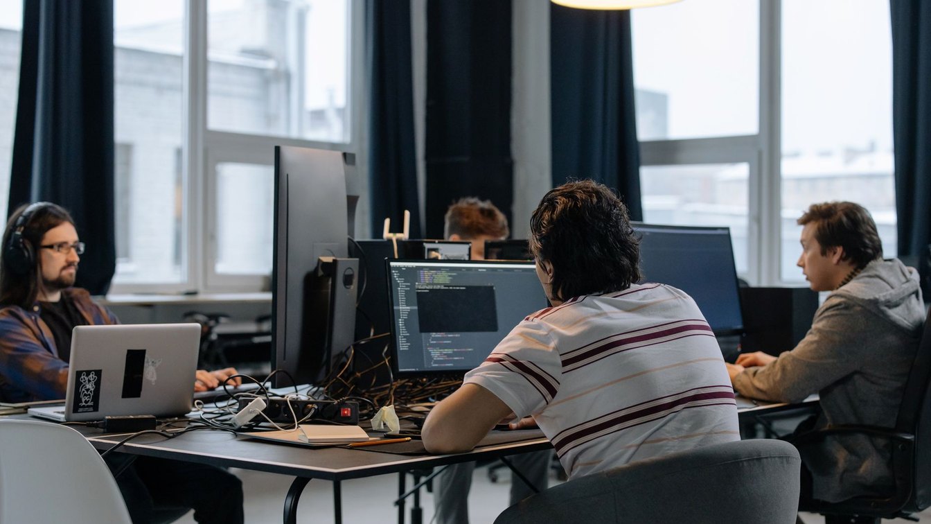Une équipe de développeurs qui examine du code sur plusieurs écrans dans un bureau