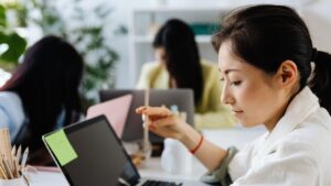 Colleagues working together at laptops in a bright, plant-filled office