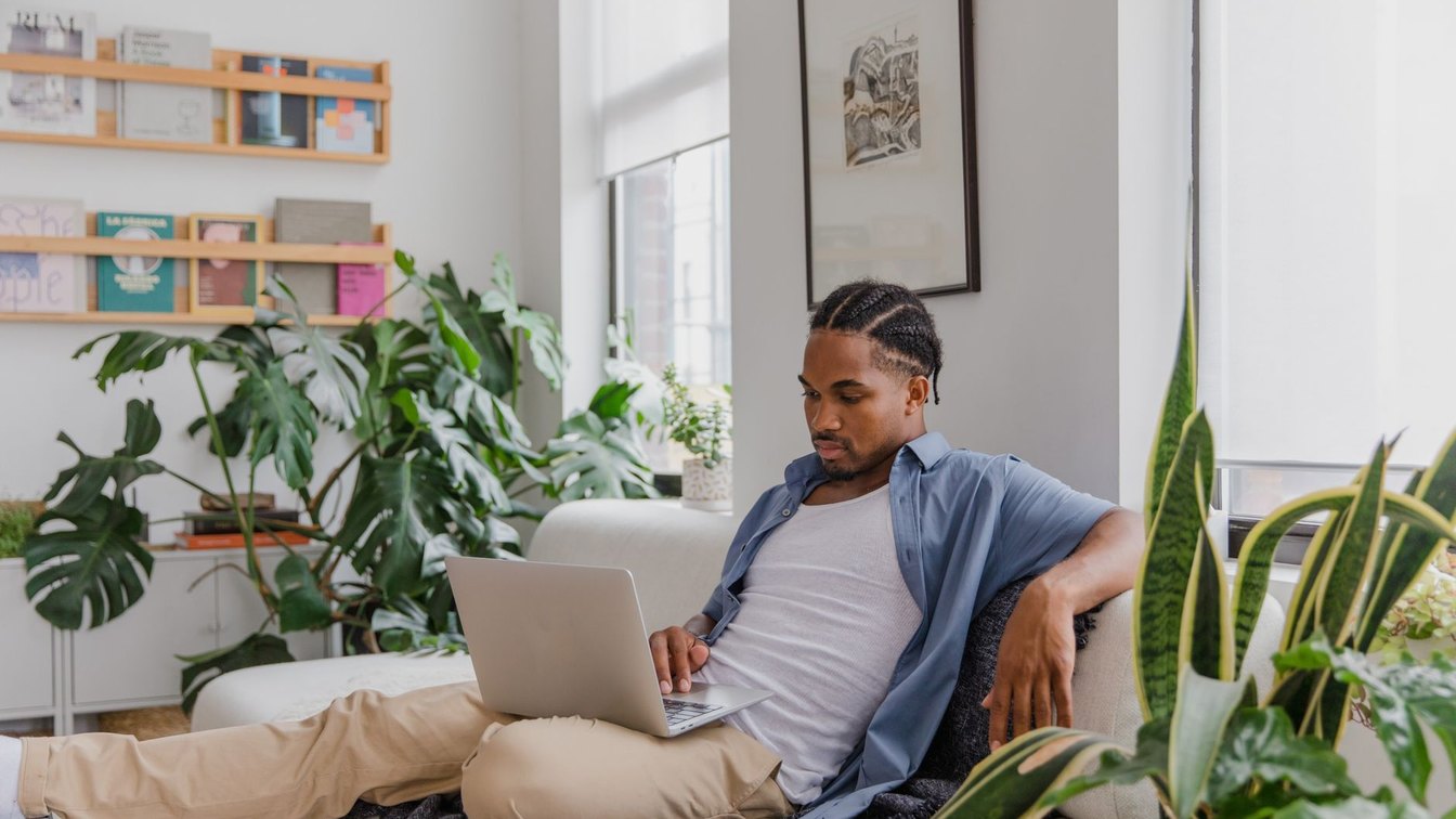 Relaxed person working on a laptop in a bright, plant-filled room