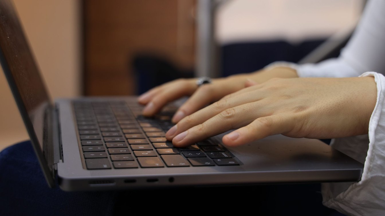 Close-up of hands typing on a laptop keyboard