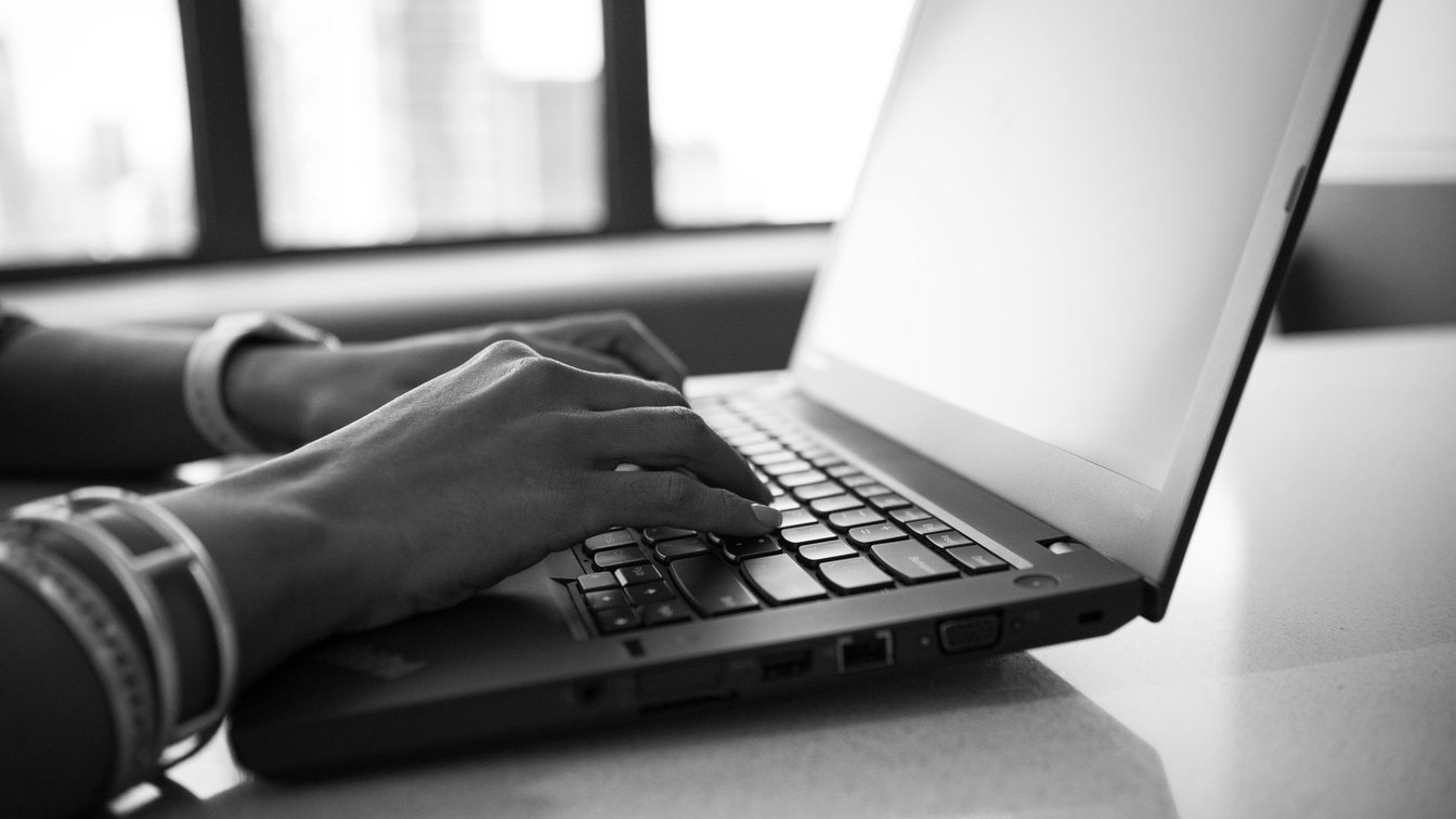 Close-up of hands typing on a laptop keyboard
