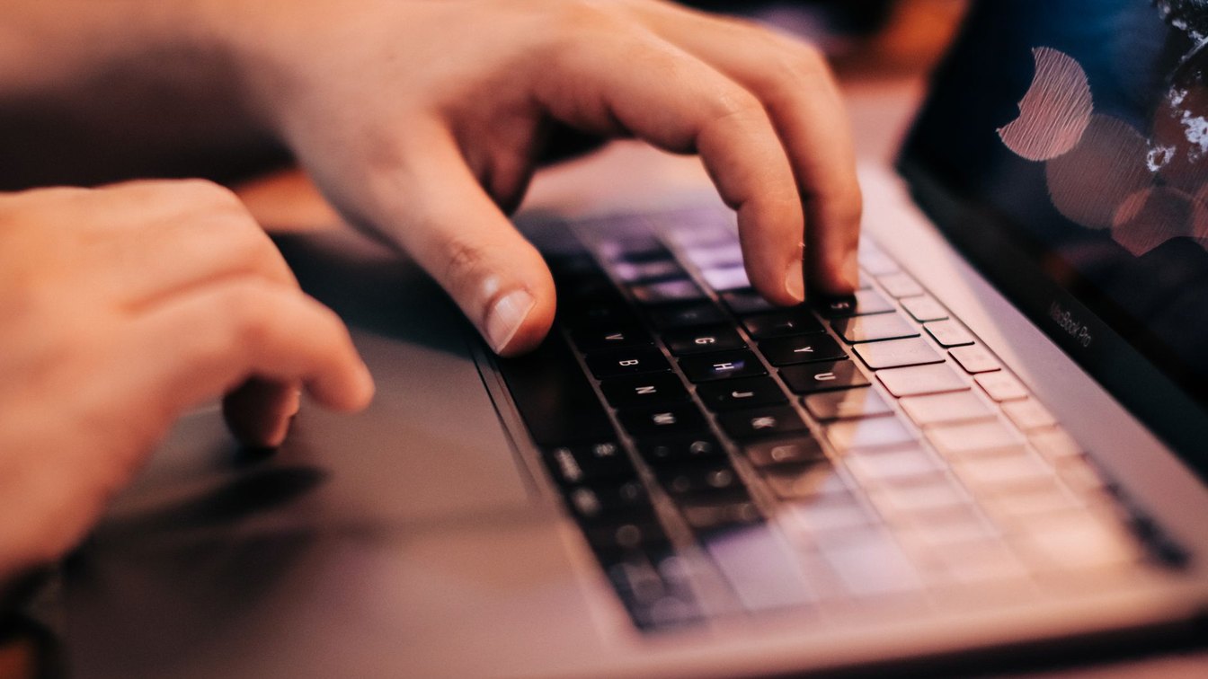 Close-up of a person's hands typing on a laptop keyboard